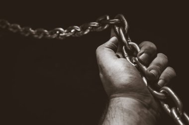 Zincire vurulmuş yetişkin bir adamın eli. Kölelik kavramı. İnsanların fikirlerinin mücadelesi ve zorlukları.