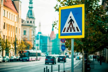 Arkasında bulanık şehir olan mavi yaya geçidi trafik levhası