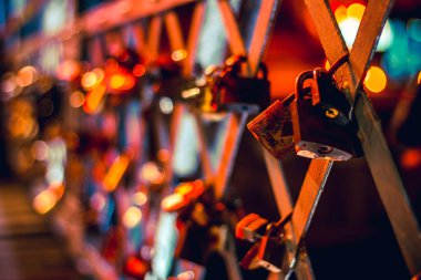 Geceleri neon ışıklarıyla aydınlatılan bir köprüye kilitlenmiş birkaç asma kilit.