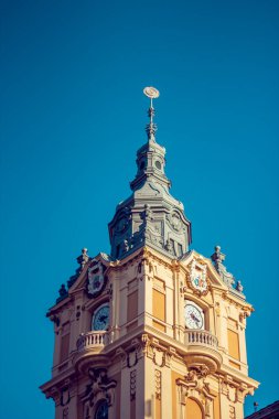 Klasik Cluj saat kulesinin dikey çekimi. Önde parlak güneşli bir günde, arka planda mavi gökyüzü var.