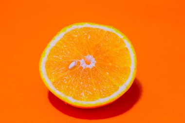Yarısı dilimlenmiş portakal ve ortasında küçük bir portakal çekirdeği..