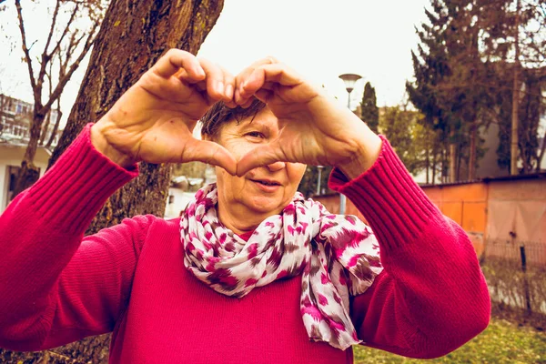Счастливая Здоровая Пожилая Женщина Смотрящая Сквозь Сформированное Пальцами Сердце Милая — стоковое фото
