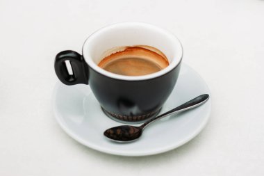 Yeşil kahve fincanı, beyaz arka planda küçük bir kaşık üzerinde sıcak, lezzetli ve tatlı bir içecek kahvaltıda köpükle servis ediliyor. Enerji için taze siyah içecek.