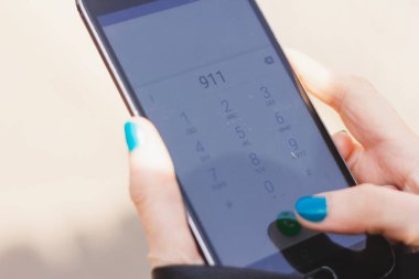 911 'i ararken elinde akıllı telefon tutan genç bir kadın acil servisi arıyor.