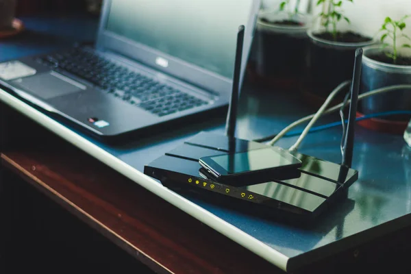 Üzerinde akıllı telefon ve arka planda dizüstü bilgisayarı olan siyah kablosuz bilgisayar veri paylaşımı için Wi-Fi Concept görüntüsü ile bağlanmış çok modern taşınabilir cihaz.