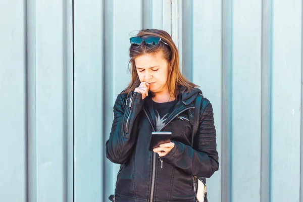 Deri Ceketli Genç Bir Kadın Akıllı Telefon Tutuyor Bir Eliyle — Stok fotoğraf