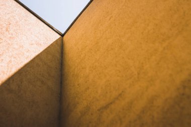 Her ikisine de uzanan sarı duvarları ve gölgesi olan iki binanın köşesi. Geometrik çizgilerle soyut mimari arkaplan
