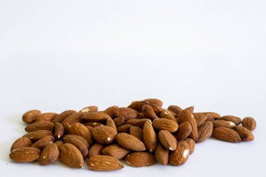 Fotokopi alanı olan beyaz bir zemin üzerine yerleştirilmiş kuru kahverengi bademler. Lezzetli ve tatlı tohumlar dolusu sağlıklı yağ ve vitamin.