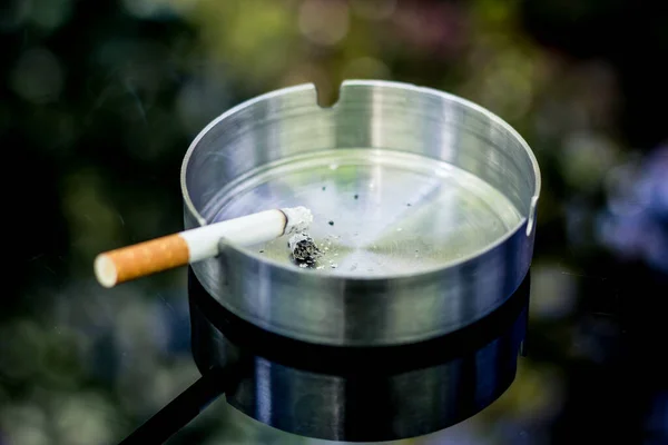 Lit Τσιγάρο Ένα Άδειο Μεταλλικό Τασάκι Κάθεται Ένα Ματ Μαύρο — Φωτογραφία Αρχείου