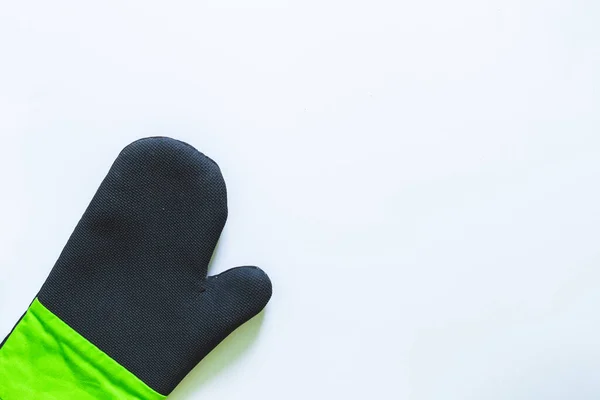 Black and green oven glove with rubber covering for protection against heat when cooking. Kitchen mitt made from thick fabric and silicone to prevent burns