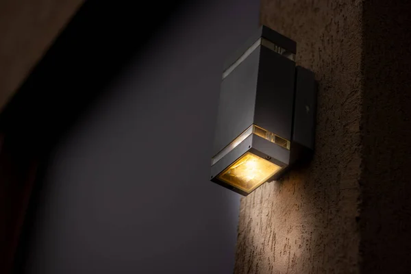 Gece yarısı fotokopi alanı olan bir binanın dış tarafına yerleştirilmiş kübik görünümlü bir fener. Aydınlanma için modern elektrik ekipmanları