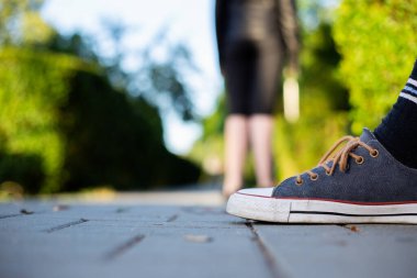 Renkli bağcıklı şık spor ayakkabılar. Pahalı ayakkabıları olan düşük seviyeli bir adam güneşli bir günde parkta dikiliyor.