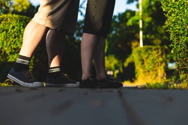 Genç bir çift, kavga ederken kaldırımda dikiliyor. Kadın açık havada tartıştıktan sonra erkeğin arkasında oturuyor. Affetme konsepti resmi