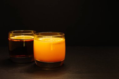 Siyah arka planda bardakta kokteyl içecekler. Alkolik ya da alkolsüz. Ardesia taş tahtasında bir dilim portakal suyu.