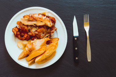 Cordon bleu 'lu haşlanmış patates. Ev yapımı tavuk eti ve haşlanmış sebzeyle porselen tabakta çatal bıçak takımının yanında servis edilir.