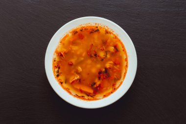 Siyah ardezya taşının üzerinde beyaz bir porselen tabakta fasulye çorbası. Yemek arkaplanı ve ortasında yemek.