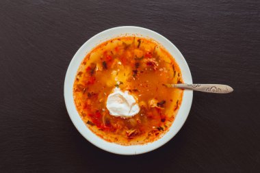 Koyu ardezya taşının ortasında ekşi kremalı fasulye çorbası. Yemek arkaplanı ve siyah baharat.