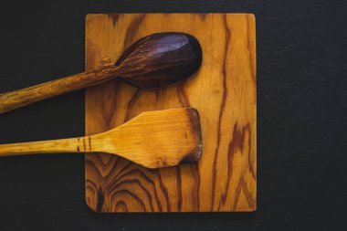 Üzerinde kullanılmış mutfak aletleri olan ahşap kare kesme tahtası. Kaya desenli levhada kırsal yemek ekipmanları