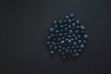 Siyah taşlı arka planda küçük taze meyveler. Sağlıklı bir diyette vitamin ve besin kaynağı olarak yabanmersini.