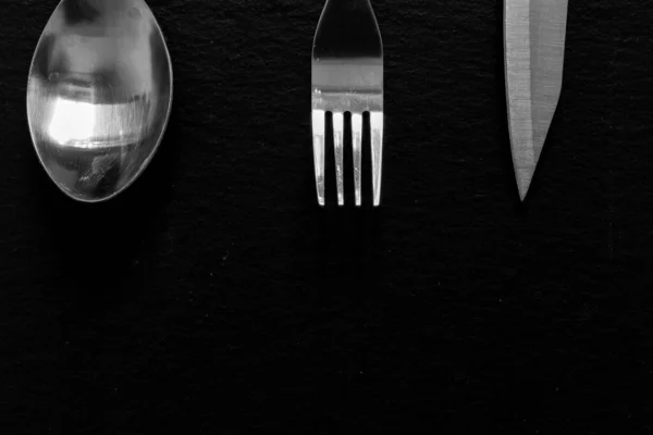 コピースペースのある暗い背景に上に配置された光沢のあるシルバーウェア 石のテクスチャ表面上のキッチンツール ステンレススプーン フォーク ナイフをきれいにする — ストック写真