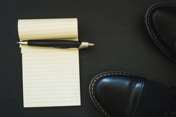 黒い革の男性の靴ノートとペンのコピースペースと暗い背景にそれらの横に配置されます 時間管理の概念像 — ストック写真