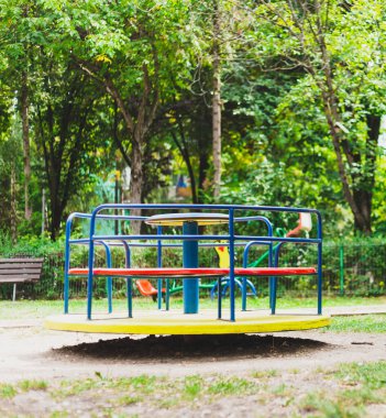 Bir yaz günü çocuk parkından renkli metalik dönen tekerlek. Parktaki çocuklar için güvenli bir eğlence oyuncağı. Eğlenceli ve neşeli bir aktivite.