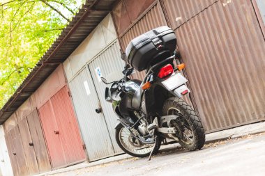 Küçük plastik taşıyıcılı motosiklet, fotokopi alanı olan garajların önüne park edilmiş. Şehirde küçük ve hızlı ulaşım araçları ya da seyahatler. Kullanışlı ve aracı kontrol etmek kolay