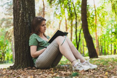 Gözlüklü genç ve güzel bir kadın bir yaz günü doğada kitap okuyor. Kahverengi saçlı sıradan giyinmiş genç kız parkta öğreniyor. Eğitim için resim kavramı