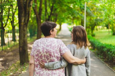 Mutlu anne ve kız bir bahar günü parkta yürürken birbirlerine sarılıyorlar. Tatlı kız ve güzel yaşlı kadın rahatlıyor ve dışarıda iyi hissediyorlar.