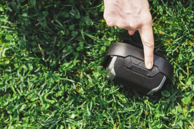 Müziğin sesini açmak için parmağın portatif bir hoparlöre dokunuyor. Yerdeyken kablosuz hoparlör ses ayarlaması