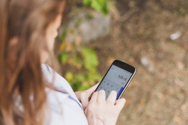 İş kadını ekrana dokunurken telefon hesap makinesiyle matematik yapıyor. Muhasebe ile kişisel telefonuyla ilgilenen ofis hanımı.