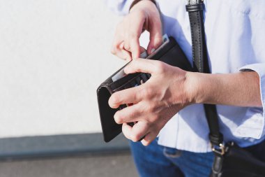 Deri cüzdanından para sayan bir iş kadını. Kız dışarıda ödeme yapmaya hazırlanıyor. Gömlek giyip çantasını takıyor.