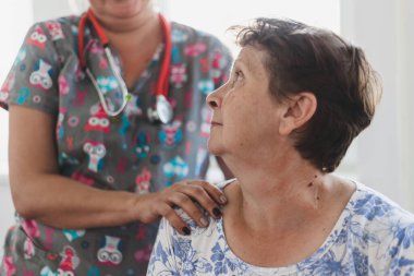 Hastanede yaşlı kadınların omzunu tutan hemşire. Kadın doktor özel bir klinikte yaşlı ve tatlı bir bayana bakıcılık yapıyor.