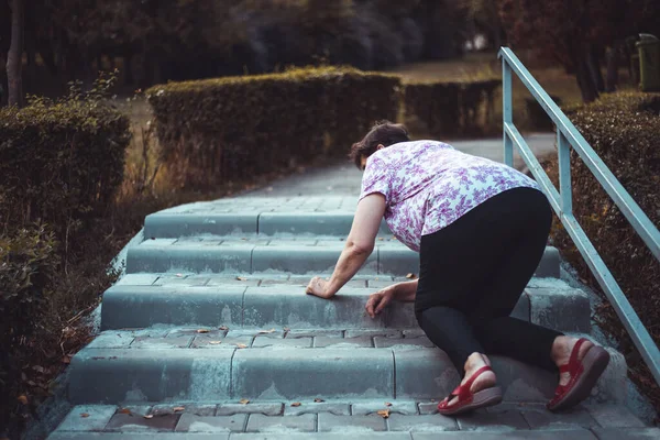 公園の外の階段に落ちてくるおばあさん 不器用な老婦人は 自然の中を歩いている間 大まかな具体的な境界線の端につまずいた 軽度事故に遭った高齢者 — ストック写真