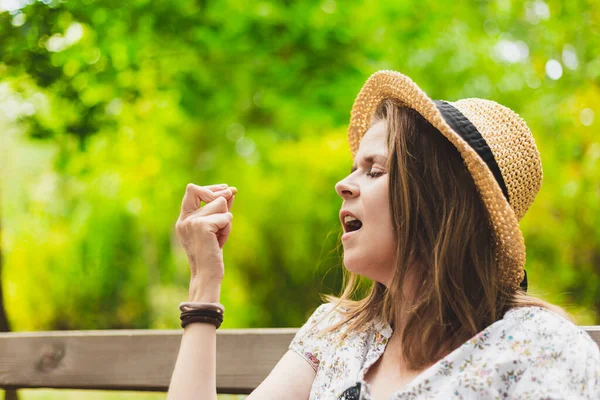 若い女性は屋外でニンニクのクローブを食べる 公園で健康的で有機的な軽食を持って夏の帽子をかぶってカジュアルに服を着た女の子 ビーガン食のコンセプトイメージ — ストック写真