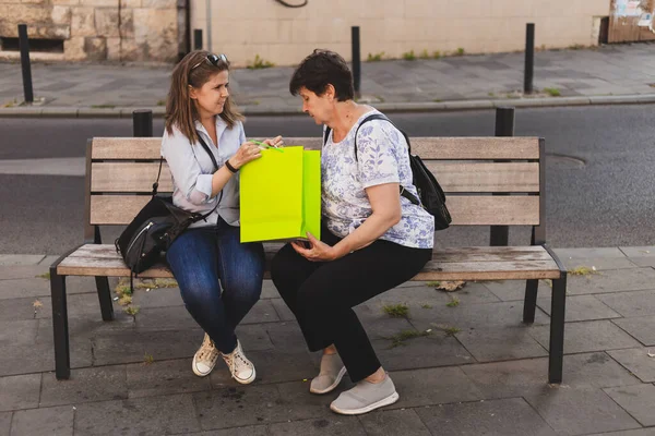 Feliz Madre Hija Sentadas Banco Mientras Buscan Una Colorida Bolsa —  Fotos de Stock