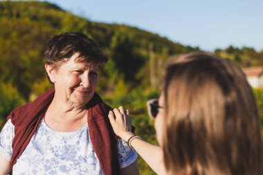 Bir yaz günü doğada yürürken konuşan anne ve kızın portresi. İki mutlu gülümseyen kadın tatilde eğleniyor ve kendilerini iyi hissediyorlar. Aile ve yaşam tarzı için kavramsal görüntü