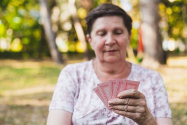Son sınıf öğrencisi dışarıda iskambil oynuyor. Yaşlı kadın dışarıda eğleniyor ve pozitif emeklilik hayatının tadını çıkarıyor. Gülümseyen büyükanne