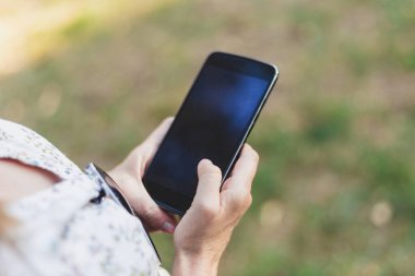 Kadın elinin ekrana dokunuşunun yakın çekimi. Dışarıda telefonu boş ekranla kullanan kişi. Düşük pil yüzünden kablosuz teknoloji aygıtı kapatıldı