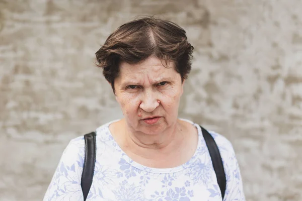 Kızgın bir yüz ifadesi olan yaşlı bir kadının portresi. Sokakta tek başına duran yaşlı bir kadın. Mutsuz, huysuz, yaşlı bir adam. Uzakta deli gibi görünüyor.