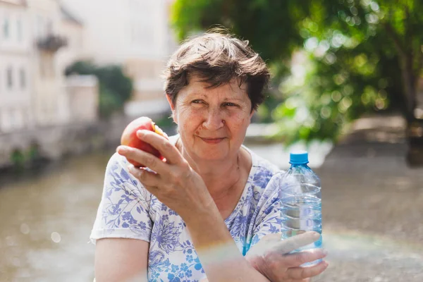 Счастливая Пожилая Женщина Ест Красное Яблоко Открытом Воздухе Солнечный День — стоковое фото