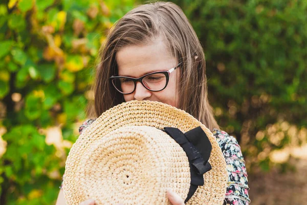 Mujer Joven Tímida Pie Parque Mientras Sostiene Sombrero Verano Contra —  Fotos de Stock