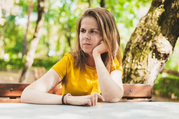 Upset young woman waiting impatiently outdoors. Angry beautiful girl sitting anxious in the park while looking in the distance on a sunny day