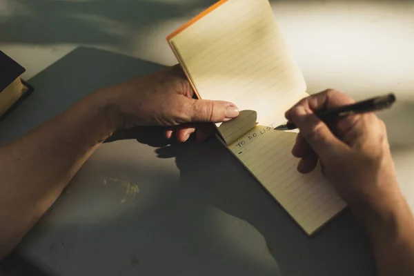 Visão Superior Pessoa Tomando Notas Caderno Branco Com Uma Caneta — Fotografia de Stock