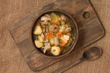 Tavuk sakatat ve ahşap kase sebze çorbası. Üstten görünüm.