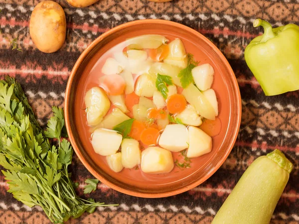 Vejetaryen sebze çorbası bir kil kase ve malzemeler üstten görünüm.