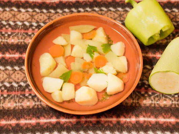 Vejetaryen sebze çorbası bir kil kase ve malzemeler üstten görünüm.