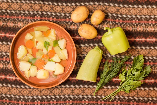 Vejetaryen sebze çorbası bir kil kase ve malzemeler üstten görünüm.