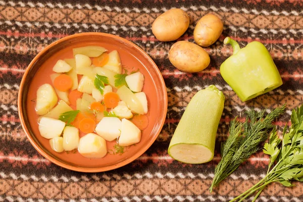 Vejetaryen sebze çorbası bir kil kase ve malzemeler üstten görünüm.