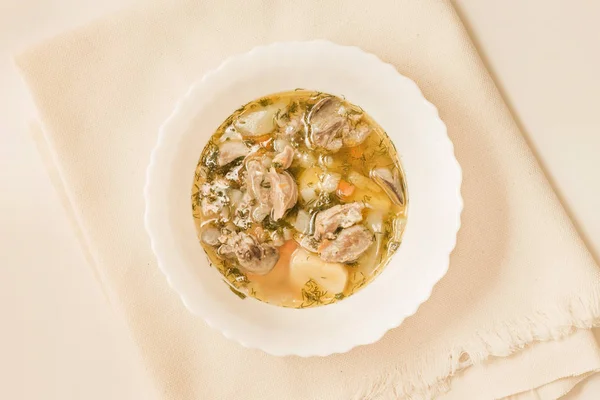 Beyaz bir kase Tavuk sakatat çorbası. Üstten görünüm.